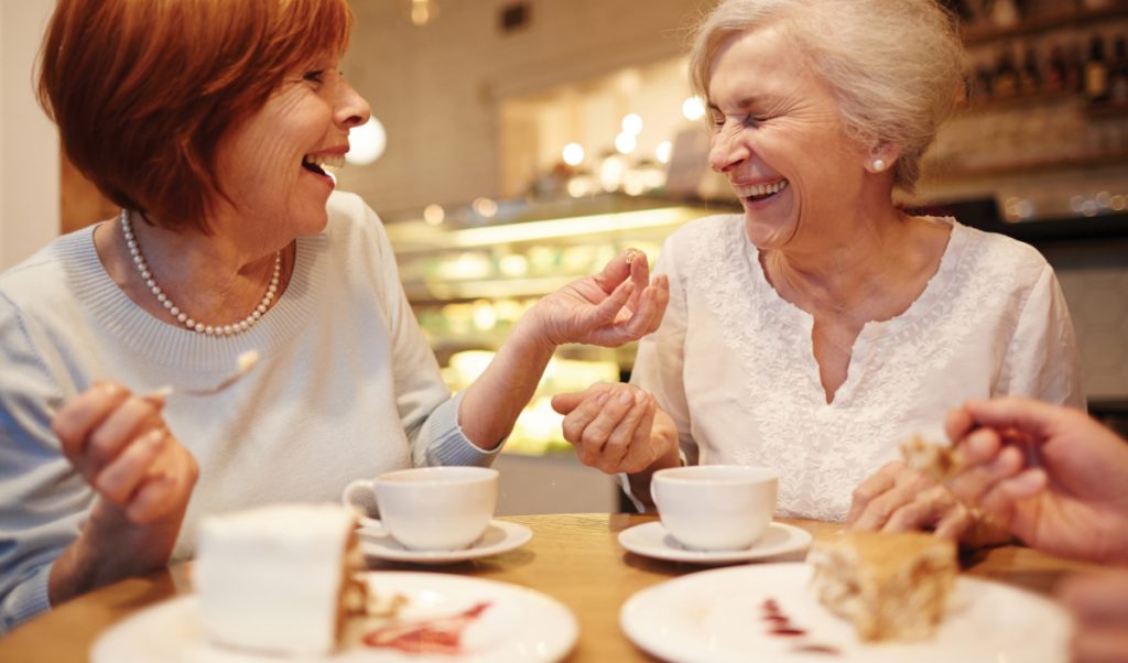 Two senior women enjoying dessert in a cafe