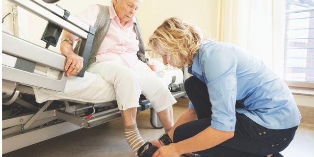 Caregiver helping a senior woman to put on her shoes