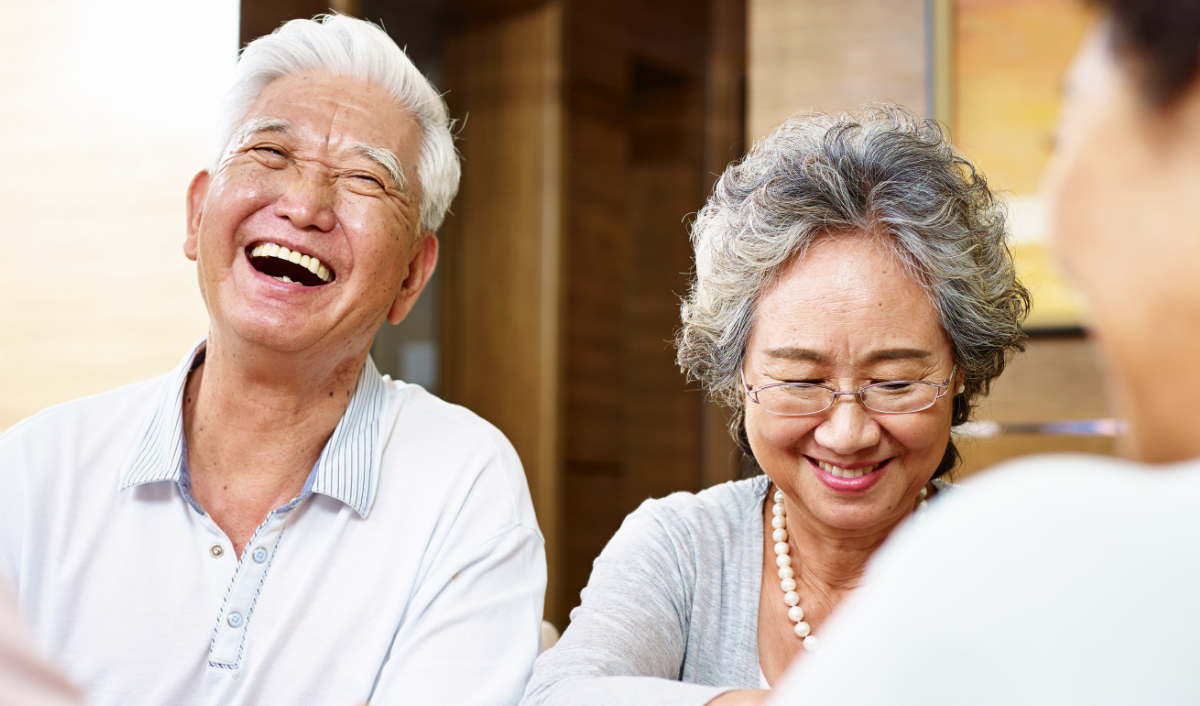 Three seniors sitting at a table laughing