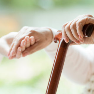 A person holding a cane and holding a person's hand
