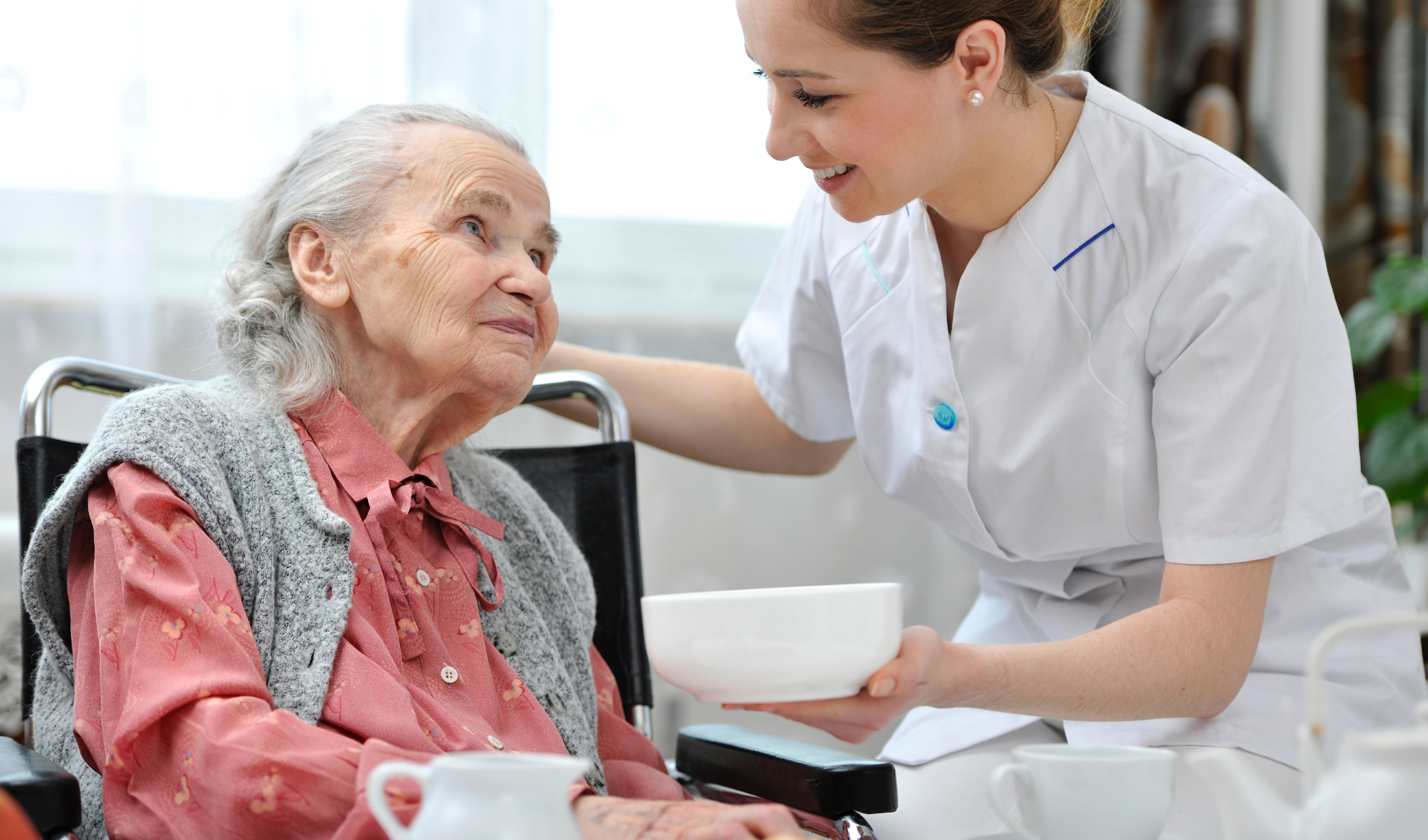 A healthcare worker helping a senior eat her meal