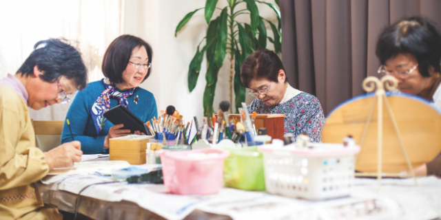 Four senior women sitting at a table doing watercolour painting