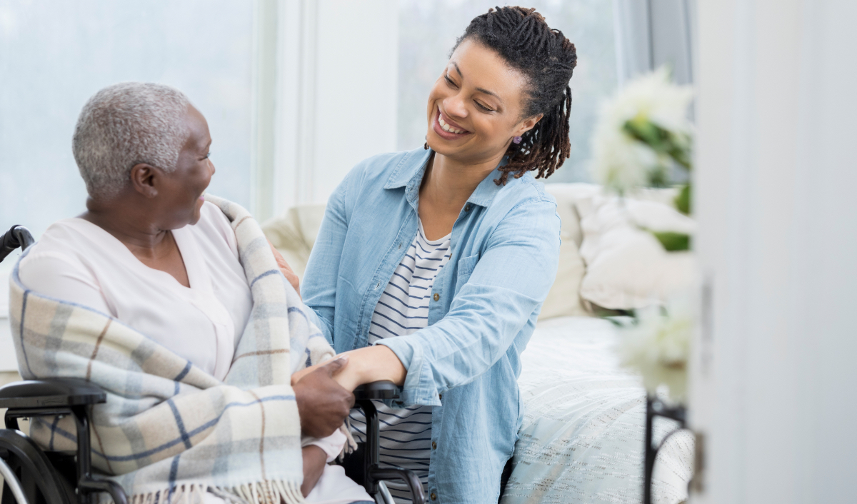 Woman visiting with a senior woman, both smiling