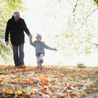 Grandfather and grandchild walking along trail in the fall.